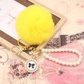 Detailed close-up of yellow faux rabbit fur pompom keychain with gold bow and pearl strap - Pearl Bowknot / Yellow