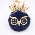 Vue macro d'un porte-clés hibou en fourrure bleu marine avec des bois dorés - Porte-clés Doré / Bleu Marine