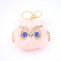 Gros plan détaillé du porte-clés hibou rose avec visage doré et yeux en pierres bleues - Porte-clés Doré / Rose