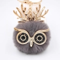 Vue détaillée du porte-clés hibou en fausse fourrure gris foncé avec bois dorés et yeux en gemme - Porte-clés Doré / Gris foncé