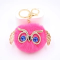 Gros plan du porte-clés hibou rose moelleux avec yeux en pierres bleues et ailes dorées - Porte-clés Doré / Rose rouge
