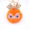 Détail macro du porte-clés hibou en fausse fourrure orange avec bois dorés et paillettes - Porte-clés Doré / Orange