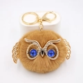 Détail du porte-clés chouette en fausse fourrure marron avec métal doré et yeux bleus - Porte-clés Doré / Café