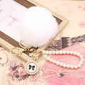 Detail showing white faux fur pompom with pearl wristband and golden bow charm - Pearl Bowknot / White