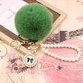Detail of green faux fur pompom keychain with pearl wristlet strap and number five charm - Pearl Bowknot / Army Green