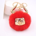 Detail of red faux fur pompom keychain with golden bull head ornament and lobster clasp - Gold Keychain / Red