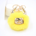 Detailed view of yellow bull faux fur pompom keychain with golden horns and hardware - Gold Keychain / Yellow