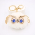 Vue détaillée du porte-clés chouette blanche en peluche avec ailes dorées et yeux bleus - Porte-clés Doré / Blanc Cassé