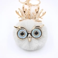 Détail du porte-clés hibou en fausse fourrure grise avec yeux bleus et bois dorés chic - Porte-clés Doré / Gris clair