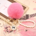 Close-up of pink faux rabbit fur pompom with pearl chain and bow pendant charm - Pearl Bowknot / Deep Pink