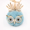 Vue détaillée du porte-clés hibou en fourrure bleue avec bois dorés et yeux brillants - Porte-clés Doré / Bleu sarcelle
