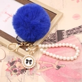 Macro detail of royal blue faux fur pompom with pearl chain and golden bow charm - Pearl Bowknot / Sapphire Blue