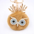 Vue détaillée du porte-clés hibou en peluche avec bois dorés et yeux à paillettes violets - Porte-clés Doré / Café