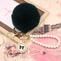 Detail of dark green faux fur pompom with pearl chain and golden bow charm keychain - Pearl Bowknot / Emerald