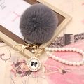 Close-up of grey faux rabbit fur pom pom with pearl strap and bow detail on gold keychain - Pearl Bowknot / Dark Gray