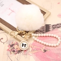 Close-up of a white faux fur ball keychain with pearl strap and bow pendant detail - Pearl Bowknot / Off-white