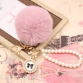 Détail du porte-clés pompon rose en fausse fourrure avec chaîne perles et nœud - Noeud de Perles / Vieux Rose