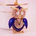 Golden alloy owl keychain with white rhinestones and blue enamel details on a white cup - Blue