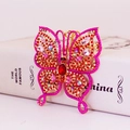 Elegante portachiavi a farfalla dorata con strass rossi appoggiato su un libro bianco - Rosa