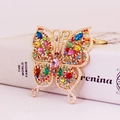 Portachiavi a farfalla dorata con strass colorati brillanti su sfondo di libro bianco - Colorato