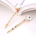 Dettaglio di fermagli dorati ondulati con cristalli a cuore su pagine di libro aperte - Bianco
