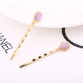 Dettaglio di due fermagli per capelli dorati con pietre ovali viola e montatura vintage - Viola