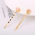Gros plan de barrettes dorées avec cercles en résine marbrée rose sur une assiette blanche - Lot de 2 Texture Marbrée Rose Orange / Rose