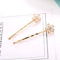 Detail of gold metal hair clips featuring sparkling flower-shaped zircons on white card - Golden Five-Petal Flower