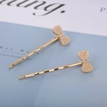 Detail shot of golden bow hair clips with white pearls and sparkling crystals on blue card - Bow Tie