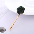 Dettaglio di un fermaglio per capelli dorato con una pallina di peluche verde e fili glitterati - Mimetico Stella Verde