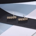 Close-up of minimalist gold-plated silver stud earrings with five round clear crystals - Single Row Gold