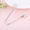 Dettaglio di fermagli per capelli a fiore in argento con zirconi su sfondo rosa tenue - Stile Mulino a Vento Argento