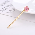 Gros plan détaillé d'une pince à cheveux fleur de cerisier dorée avec émail rose et strass - Style Fleur de Cerisier Rose