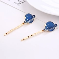 Vue détaillée de barrettes dorées avec motifs de planètes et d'étoiles en émail bleu - Style Planète Bleue