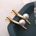 Dettaglio macro di due fermagli per capelli dorati con grandi perle bianche su vassoio - Stile 10 / Bianco perla