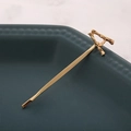 Détail d'une pince à cheveux en métal doré avec design de lettre A texturée et élégante - Lettre A