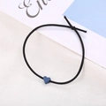 Detailaufnahme eines schwarzen elastischen Haargummis mit einer kleinen mattblauen Herzperle - Marineblau