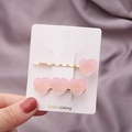 Détail de deux barrettes à cheveux en résine rose mat en forme de cœur sur carte blanche - Coeur Dégradé Rose Clair