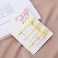 Détail de trois barrettes à nœuds en métal jaune sur une carte à motifs de fleurs - Light jaune