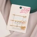 Set di tre fermagli per capelli dorati con fiocchi e strass su scheda di esposizione - Bianco Perlato