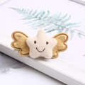 Cute felt star hair clip with yellow wings and embroidered face on white tray - Off-white