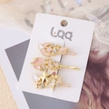 Dettaglio di fermagli per capelli dorati con stelle alate, strass e smalto su confezione - Set Pianeta Rosa Perlato