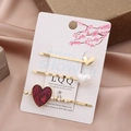 Detailed view of three heart hair clips with pearls and crystals on a display card - Fuschia