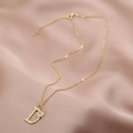 Détail d'un collier doré avec pendentif lettre D orné d'une fleur et d'un zircon - Lettre D (Chaîne D)