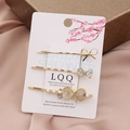 Detailed view of a three-piece gold-tone hair clip set featuring pearls and rhinestones - Green Gradient
