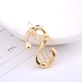 Elegant gold S-shaped hair clip with bamboo texture on a minimalist white tray - Letter S
