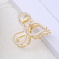 Detail of elegant gold metal hair claw with bow shape and white pearl embellishments - Bowknot Style - Pearl