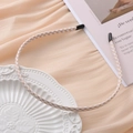Dettaglio di un cerchietto sottile in tessuto a quadretti beige con punte protettive nere - Griglia gialla