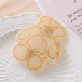 Detailed close-up of a cute acetate bear hair clip with gold mira engraving on ceramic - Beige