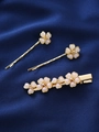 Nahaufnahme goldener Blumenhaarklammern mit Perlen auf blauem Seidenhintergrund - 3-teiliges Set / Irisierendes Weiß Set